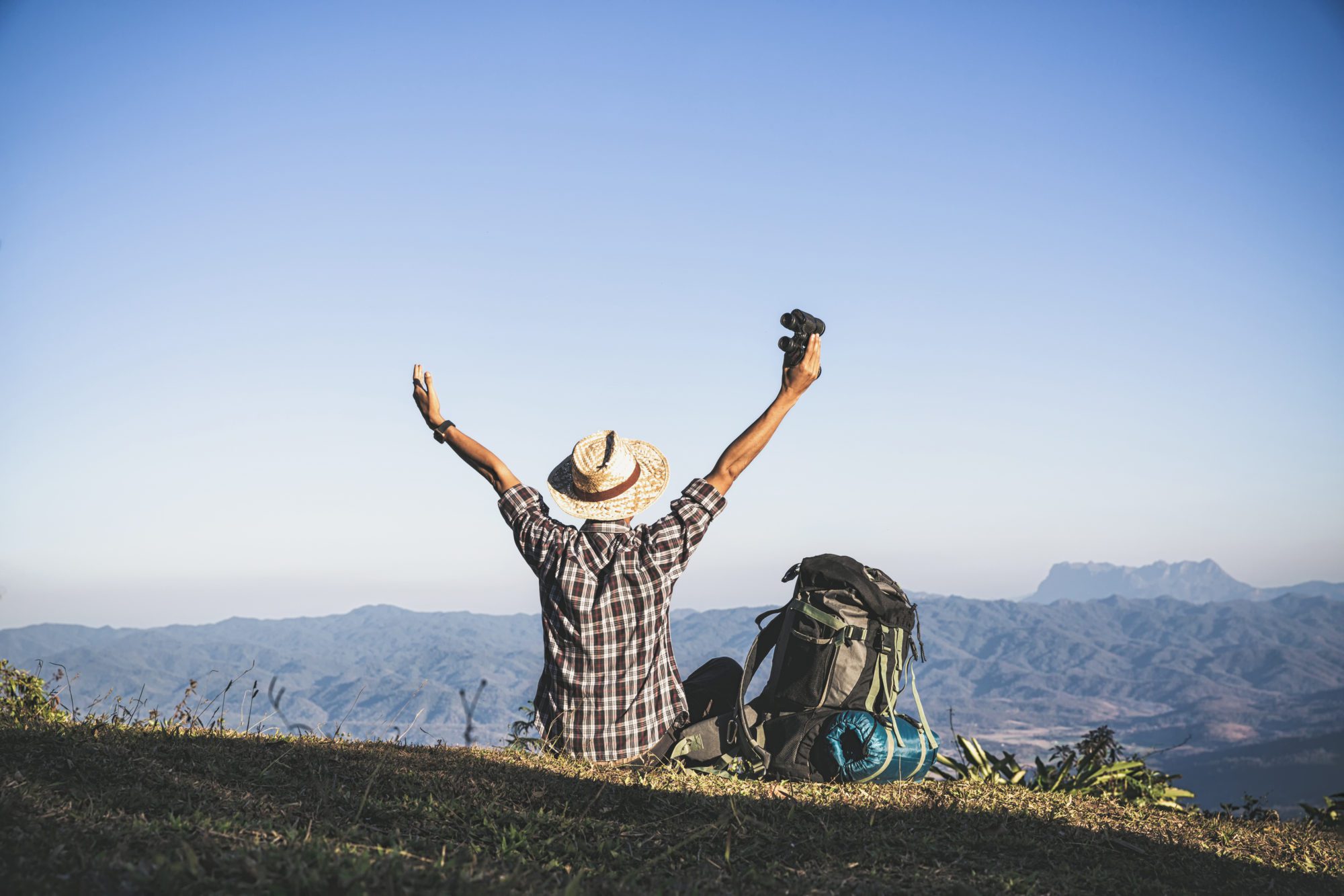 Tourist  from mountain top. sun rays. man wear big backpack agai